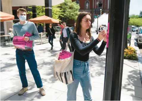  ?? EVAN VUCCI/AP ?? Students put up posters calling for student loan debt forgivenes­s on Friday near the White House.