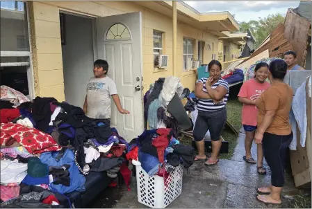  ?? PHOTO BY REBECCA SANTANA ?? Residents of apartments in Harlem Heights, Fla., clean out clothes and other possession­s from their apartments swamped by flood waters on Saturday.