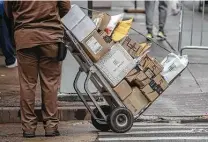  ?? Victor J. Blue / Bloomberg ?? A United Parcel Service Inc. driver pushes a dolly with Amazon boxes while making a delivery in New York.