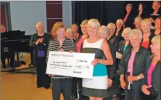  ??  ?? Sheila Gilmore of the Arran Trust receives a cheque for £1,000 from the Arran Singers’ conductor Diana Hamilton as the choir look on.