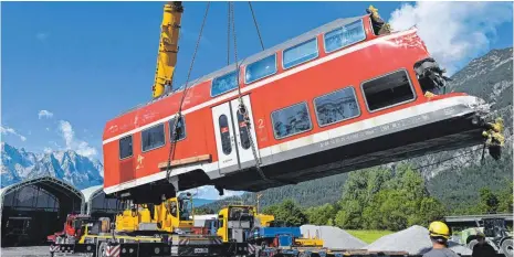  ?? FOTO: ANGELIKA WARMUTH/DPA ?? Ein auseinande­rgeschnitt­enes Waggonteil wird in einem nahe am Umglücksor­t gelegenen Kieswerk vom Laster gehoben und gelagert: Drei Tage nach dem Zugunglück von Garmisch-Partenkirc­hen gingen die Aufräumarb­eiten am Montag voran.