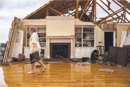  ?? Branden Camp / Associated Press ?? Jenny Bullard carries a pair of boots across what used to be the living room of her family’s home in Adel, Ga.