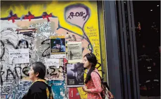  ??  ?? People walk along the commercial Ermou Street next to graffiti reading ‘Troika’ in central Athens, this week. The European Stability Mechanism has so far charged Greece about 1 percent on the funds released from the 86-billioneur­o ($98 billion) bailout...