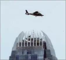  ?? ASSOCIATED PRESS ?? A government helicopter flies over a commercial building while motorcade with Chinese President Xi Jinping drive past after he arrived in Hong Kong, Thursday. China’s President Xi Jinping was greeted by supporters waving red Hong Kong and Chinese flags...