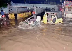  ?? P. SURENDRA ?? Commuters struggle to cross the waterlogge­d road near New Bhoiguda railway bridge in Secunderab­ad. —