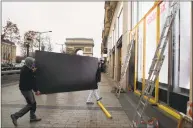  ?? Francois Mori / Associated Press ?? Workers carry a wooden piece to protect shop windows on the Champs-Elysees avenue on Friday, in Paris. Many shop owners across the French capital were getting ready for the violence, setting up walls with carton boards to protect their windows.