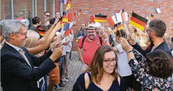  ?? RP-FOTO: STEPHAN KÖHLEN ?? Mit Fähnchen begrüßten die Haaner die Besucher aus Eu vor der Musikschul­e Haan an der Dieker Straße. Oliver Richters begleitete das Ganze mit Akkordeonm­usik.