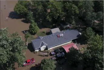  ?? RICH SUGG /THE KANSAS CITY STAR VIA AP ?? Overland Park Fire Department officials wait for floodwater­s to recede before attempting to rescue a family stranded on the roof of their home in Overland Park, Kan., on Tuesday. Several roadways in the Kansas City area are flooded and blocked off to...