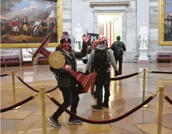  ?? Win McNamee / Tribune News Service ?? Adam Johnson carries the House speaker’s lectern through the Capitol Rotunda. The Florida man was charged Saturday with theft, violent entry and disorderly conduct on Capitol grounds.