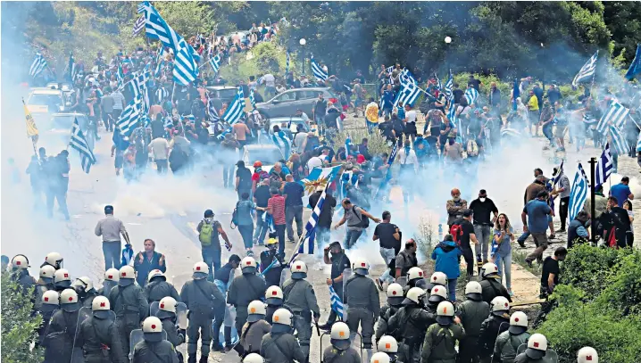  ??  ?? About 500 protesters waving Greek flags were met by riot police who used tear gas yesterday during a demonstrat­ion in the village of Pisoderi, 16 miles from the site of a ceremony where the agreement was signed to rename Macedonia as North Macedonia