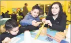  ?? Arnold Gold / Hearst Connecticu­t Media ?? From left, John Lopez, 3, and his brother, Jason, 9, learn how experiment­s work with Southern Connecticu­t State University sophomore Amy Orenstein at Family Science Night at Hill Central School in New Haven on Wednesday.