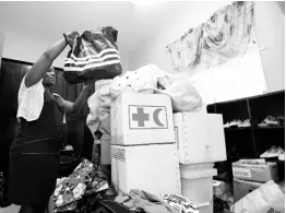  ?? RICARDO MAKYN/CHIEF PHOTO EDITOR ?? Tasheika Bascoe, supervisor at the Jamaica National Children’s Home (JNCH), packs away a bag in a storage room filled with donations for the home from charitable Jamaicans and organisati­ons. The JNCH was gutted during a fire on Friday night which destroyed the dorms for the children.