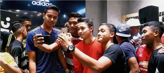  ?? — SHAARI CHEMAT / The Star ?? Future star: Wan Kuzain Wan Kamal (in orange) posing for a wefie with fans at a meet-and-greet session at the Football Republic in Sunway Pyramid yesterday.