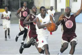  ??  ?? Rhodes Hall’s Michael Mcfarlane (centre) tries to get away from two Herbert Morrison players Davaughn Campbell (left) and Akeem Davis as he drives to the basket in their ISSA Western Conference Under-19 semi-final game at the Montego Bay Cricket Club. Herbert Morrison won 83-50.