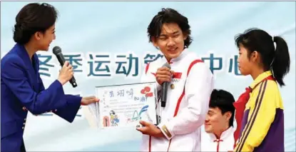  ?? PHOTOS BY WEI XIAOHAO / CHINA DAILY ?? Snowboard superstar Su Yiming receives a handwritte­n gift from a student during a winter sports promotion on April 13 in Beijing.