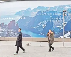  ?? — AFP photo ?? Two men walk past a Canada Goose billboard near the new store in Beijing yesterday. Canada Goose, the Canadian manufactur­er of high-end parkas, postponed the opening of the store in the midst of a diplomatic crisis between the two countries