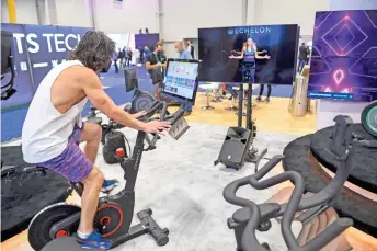  ?? — AFP photos ?? An attendee rides an Echelon exercise bike while an instructor is displayed on screen during the CES tech show in Las Vegas, Nevada. The connected fitness industry has shown some sensitivit­y to the changing conditions of the pandemic and the way it affects equipment users’ lives.