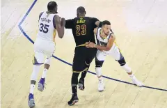  ?? AFP ?? The Cavs’ LeBron James runs past the Warriors’ Kevin Durant, left, and Stephen Curry.