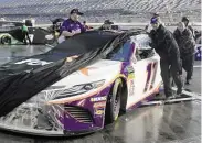  ?? Phelan Ebenhack / Associated Press ?? Denny Hamlin’s crew pushes his car back to the garage area after rain postponed the Daytona 500.