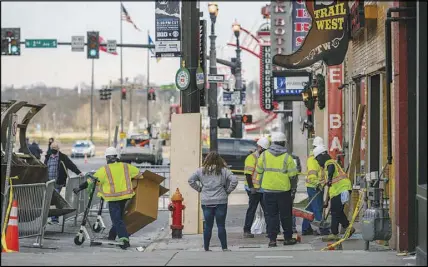  ?? WILLIAM DESHAZER / THE NEW YORK TIMES FILE (2020) ?? A work crew on Dec. 28, 2020, cleans up at a store damaged in the bombing. About 50 buildings in Nashville’s historic district were damaged.