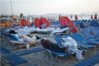  ?? Petros Giannakour­is / Associated Press ?? Tourists sleep on sun beds at a beach on the Greek island of Kos on Saturday, a night after an earthquake killed two tourists and injured nearly 500 others across the Aegean Sea region.