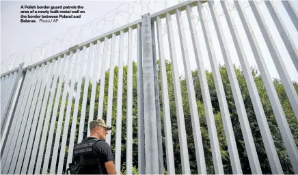  ?? ?? A Polish border guard patrols the area of a newly built metal wall on the border between Poland and Belarus. Photo / AP