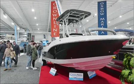  ?? DANA JENSEN/THE DAY ?? Visitors check out a Finseeker 210CC power boat at the Oxbow Marina booth Saturday during the Hartford Boat Show at Mohegan Sun. Oxbow Marina is located in Northampto­n, Mass.