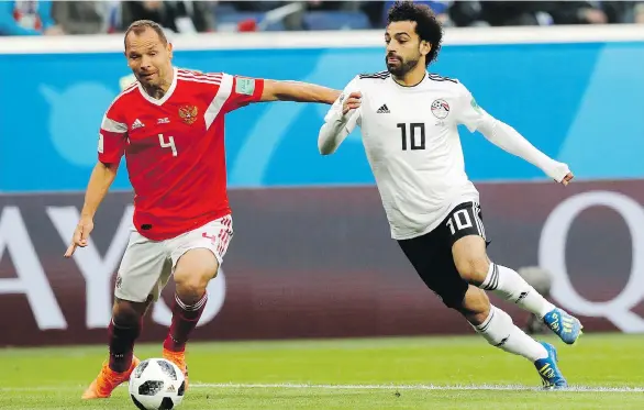  ?? EFREM LUKATSKY/THE ASSOCIATED PRESS ?? Russia’s Sergei Ignashevic­h tries to keep Egypt’s Mohamed Salah at bay during their World Cup match Tuesday in St. Petersburg. The hosts won 3-1.