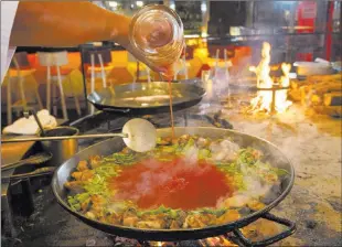  ??  ?? Montesinos adds tomato puree as he prepares a classic paella.