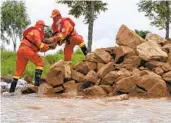  ?? ZHANG TAO XINHUA NEWS AGENCY VIA AP ?? Firefighte­rs use rocks to build a barrier against floodwater­s in northeaste­rn China on Saturday.