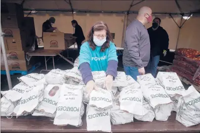  ?? MARK MIRKO PHOTOS/HARTFORD COURANT ?? A volunteer stacks potatoes on April 20 at Rentschler Field. About 1,000 cars lined up for a Foodshare distributi­on of 35,000 pounds of food.