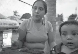  ?? AP ?? Sitting with her son, Pedro, Buena Ventura Martin-Godinez, from Guatemala, shows a photograph of her daughter, Janne, on her phone in Homestead, Florida. Janne was placed in Michigan after crossing the U.S. border with her father.