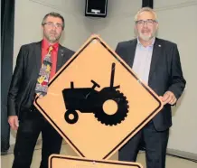  ??  ?? Le 1er vice-président James Allen et le président Paul Doyon entourant le nouveau panneau de signalisat­ion routière des producteur­s de la Chaudière-Appalaches.