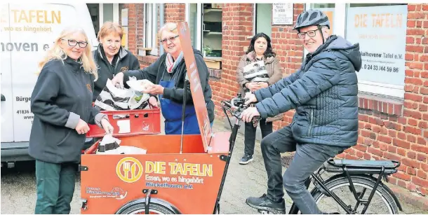  ?? FOTO: RUTH KLAPPROTH ?? In das Lastenrad verstaut die stellvertr­etende Leiterin Elisabeth Lüpges (2.v.L.) mit Helferinne­n Lebensmitt­eltüten. Klaus Peters fährt die Touren.