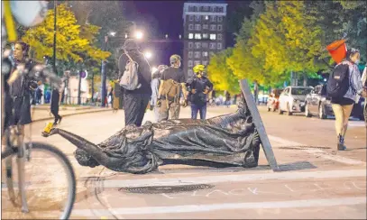  ?? Emily Hamer The Associated Press ?? Wisconsin’s “Forward” statue lies Tuesday in the street on Capitol Square in Madison, Wis., after protesters tore it down.