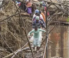  ??  ?? A soldier assists villagers to cross a make-shift bridge in the wake of Cyclone Idai in 2019