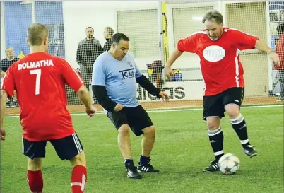  ?? VLADO ZAMECNIK/Special to the Herald ?? Norman Peters, right, of Theos, tries to pull away from Duarte Francisco of TC Auto Sales as Theos’ Roland Kruger looks on Sunday at the Adidas Sportsplex.Theos won 10-4.