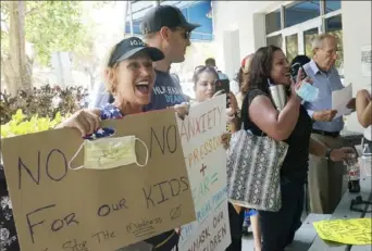  ?? Marta Lavandier/Associated Press ?? Joann Marcus, of Fort Lauderdale, Fla., left, protests mask mandates as she listens during the Broward School Board’s emergency meeting on Wednesday.