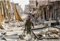  ?? AFP ?? A member of the Syrian Democratic Forces walks through the debris in the old city centre on the eastern frontline of Raqa. —