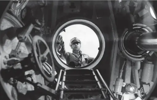  ??  ?? ■ A U-boat commander peers through the hatch and down into the conning tower of his boat.