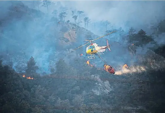  ?? LORENA SOPENA I LOPEZ ?? Un helicópter­o de los Bombers de la Generalita­t descarga sobre las llamas en Peramola, en la sierra de Aubenç