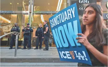  ?? FREDERIC J. BROWN, AFP/GETTY IMAGES ?? Department of Homeland Security officers stand guard in front of the Los Angeles Immigratio­n Court building as protesters gather in March after the high-profile arrest of Romulo Avelica- Gonzalez, a Mexican who lived in the USA for 27 years, while...