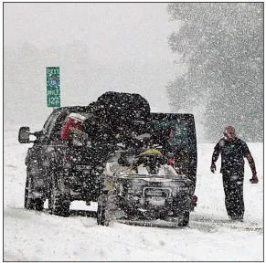  ?? AP/ROBERT RAY ?? People on Interstate 26 near Savannah, Ga., attend to their vehicle as heavy snow falls Wednesday during a winter storm that smacked parts of Florida, Georgia and South Carolina. The storm is predicted to roll up the East Coast, carrying possible...