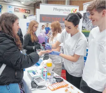  ?? FOTO: STILLER ?? Nur nicht hinschauen: Einer Schülerin wird am Stand der Pflegeschu­le Wangen ein Tropfen Blut zur Bestimmung des Zuckerspie­gels abgenommen. Ganz praktisch wurde also um Auszubilde­nde geworben.