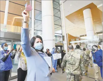  ?? Matthew Brown / Hearst Connecticu­t Media ?? Kathleen Silard, president and CEO of Stamford Health, waves a flag as she watches military personnel parade past to cheers and salutes from Stamford Hospital staff on May 19.