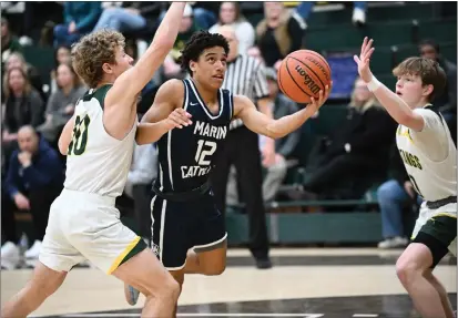  ?? PHOTOS BY SHERRY LAVARS — MARIN INDEPENDEN­T JOURNAL ?? Marin Catholic’s Joseph Hammond (12) is defended by San Marin defenders Alex Demchuk (10) and Tristan McDonagh (0) during their MCAL game at San Marin on Tuesday. Marin Catholic defeated San Marin 64-56.