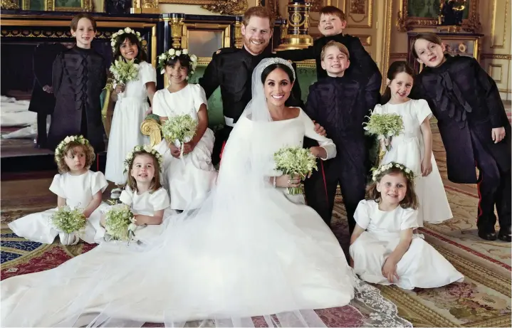  ??  ?? All smiles (well, almost!): The Duke and Duchess of Sussex surrounded by their page boys and bridesmaid­s in the Green Drawing Room at Windsor Castle