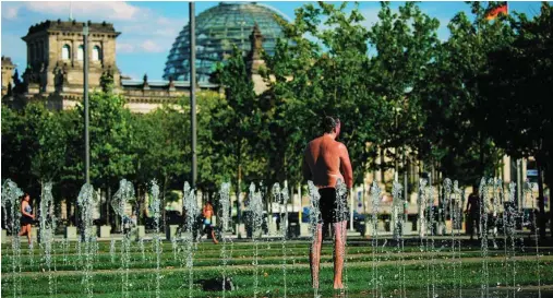  ?? REUTERS ?? Un hombre se refresca en una fuente frente al edificio del Bundestag, en Berlín, ayer
