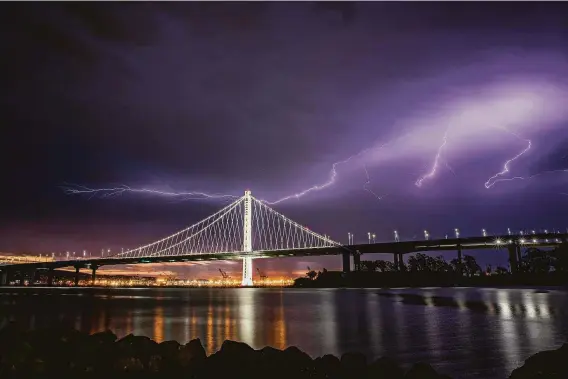  ?? Carlos Avila Gonzalez / The Chronicle 2020 ?? Lightning illuminate­s the sky over the Bay Bridge as a storm passes through in 2020. Historic lightning-sparked wildfires erupted across the state that year.