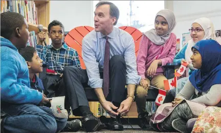  ?? MARK BLINCH/THE CANADIAN PRESS ?? Finance Minister Bill Morneau takes part in the pre-budget ceremony of putting on new shoes at Nelson Mandela Park Public School in Toronto on Monday. Morneau says the budget will introduce “new measures that will be important for Canadian families.”